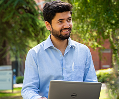 UCD student sitting outside with a laptop.